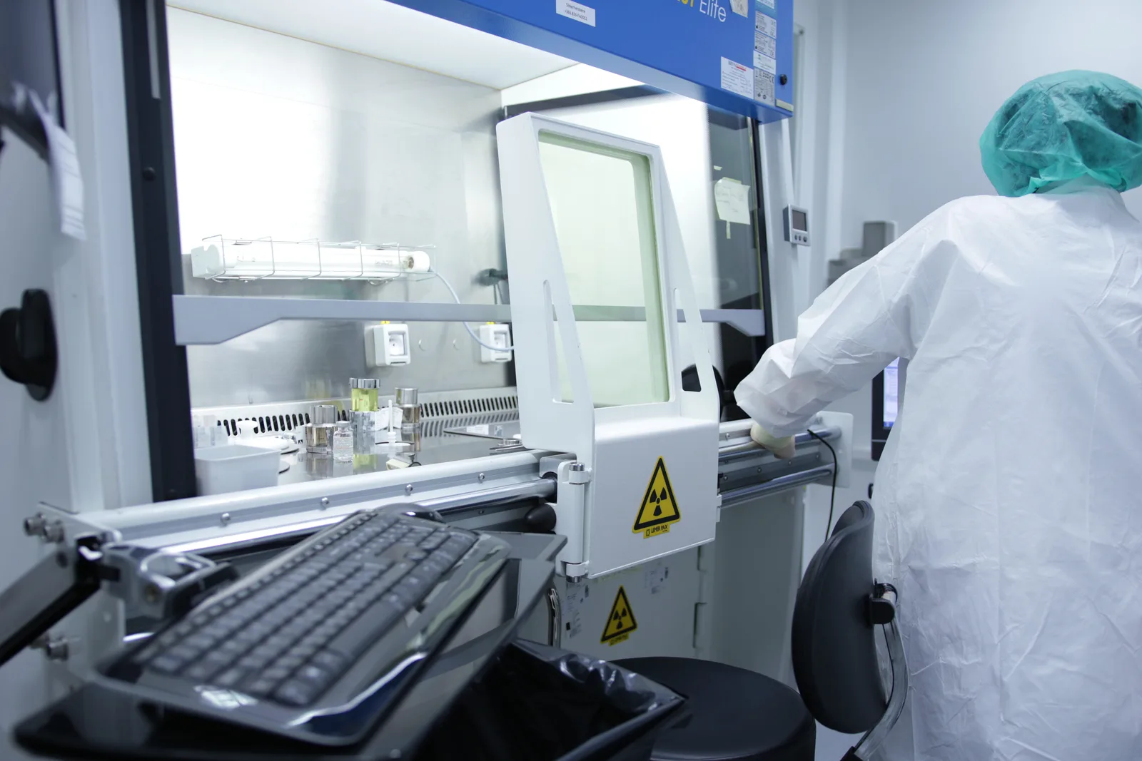Gowned laboratory technician operating a biosafety cabinet in a pharmaceutical cleanroom